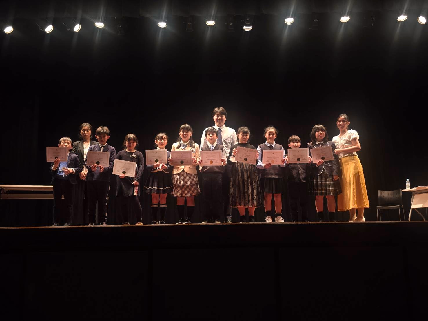 Students and teachers celebrating together on stage at the Speech Contest