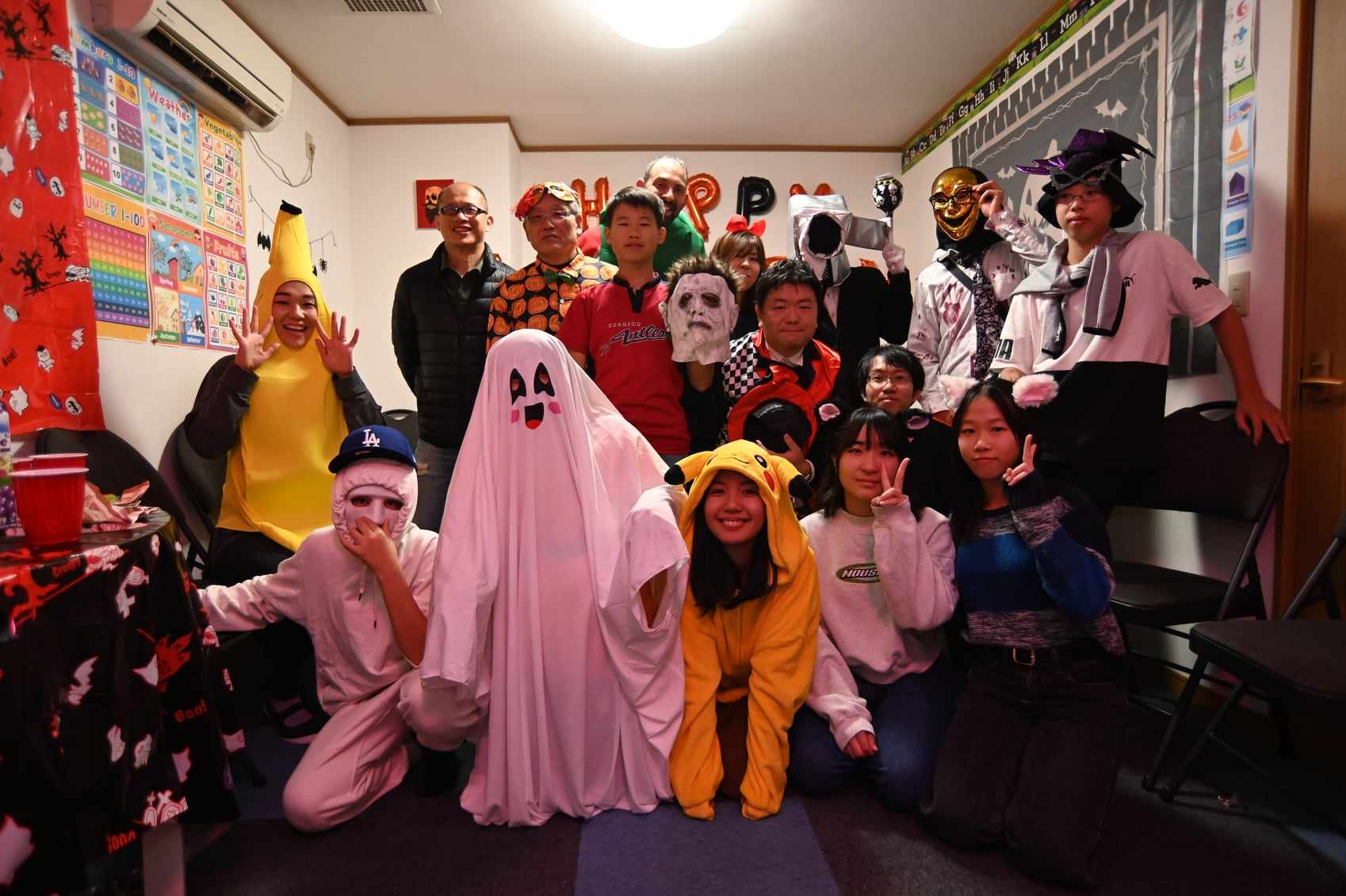 ハロウィーンの仮装で一緒にポーズをとる生徒と先生たち